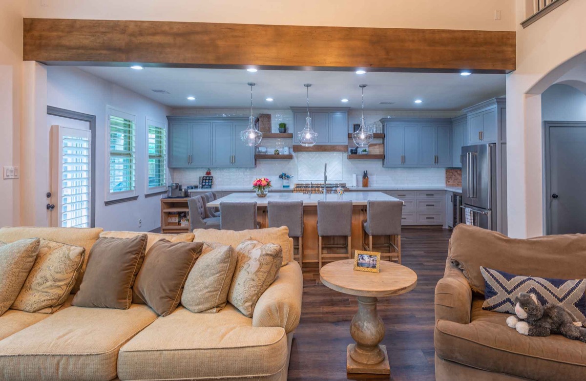 Open concept kitchen and living room remodel with wood beam and blue cabinetry in Houston
