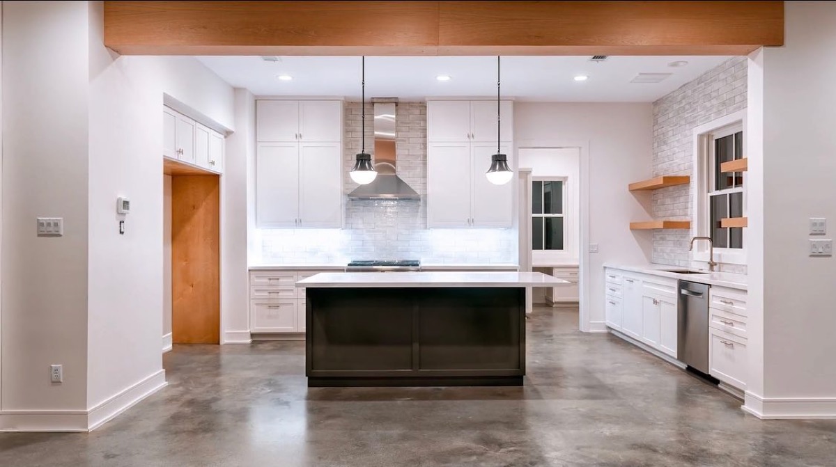 Modern kitchen with dark island and polished concrete floors in Houston