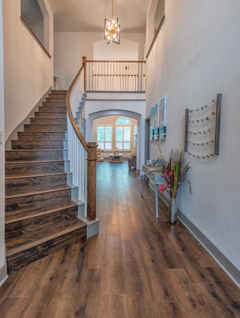 Grand entryway with curved staircase and hardwood flooring by Crafted Kitchens