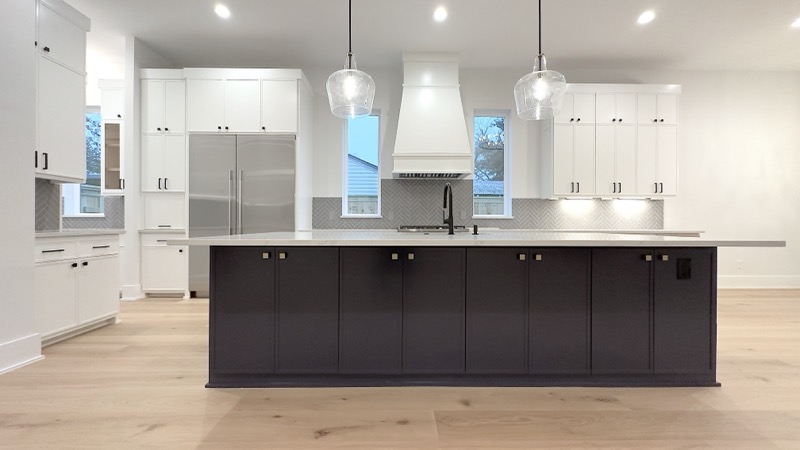 Modern white kitchen with dark island and herringbone backsplash in The Heights, Houston