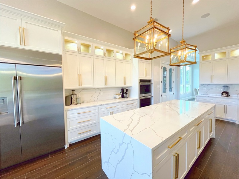 White kitchen with gold accents and quartz waterfall countertop in Houston