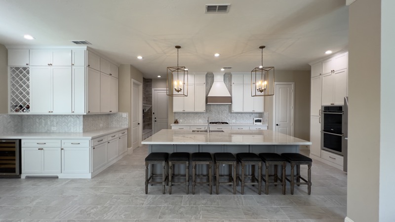 Large white kitchen with oversized island and custom cabinetry in Houston